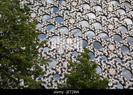 Green trees in leaf and the circular windows of Ravensbourne College (University) in Peninsular Square, on 23rd June 2017, Greenwich Peninsular, London, England. Stock Photo