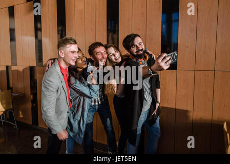Group of students making selfie in the big room standing by the window. Casual lifestule. Stock Photo