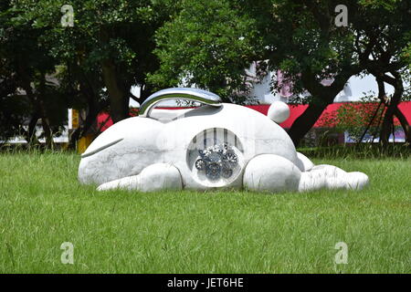 Marble sculpture of a white rabbit with cog wheel stomach and metal ears in New Taipei City Taiwan, Xinzhuang park. Stock Photo