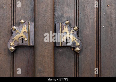 Old wooden oak arched gothic church doorway with black wrought iron hinges. Metal, wrought-iron handle on the double doors to the church. Stock Photo