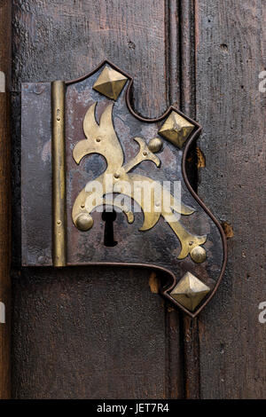 Old wooden oak arched gothic church doorway with black wrought iron hinges. Metal, wrought-iron handle on the double doors to the church. Stock Photo