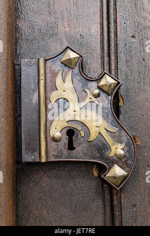 Old wooden oak arched gothic church doorway with black wrought iron hinges. Metal, wrought-iron handle on the double doors to the church. Stock Photo