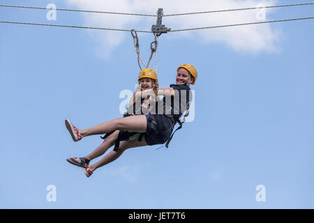 DOBRIS, CZECH REPUBLIC - JUNE 10, 2017. Young woman and girl in the seat crashes down the rope across the valley. Centre harness Stock Photo