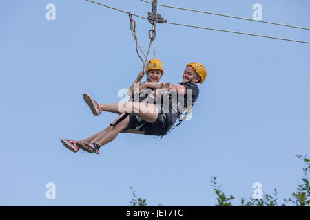 DOBRIS, CZECH REPUBLIC - JUNE 10, 2017. Young woman and girl in the seat crashes down the rope across the valley. Centre harness. Girl and woman on th Stock Photo