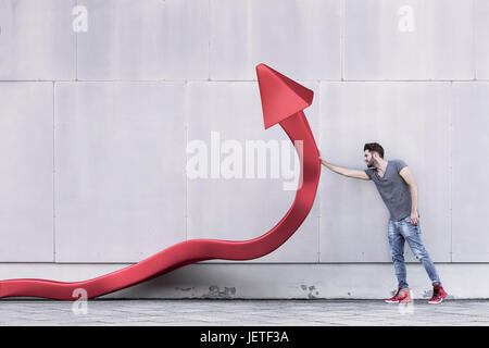 A red arrow is being pushed upwards with one hand to promote growth and rising investments of the stock market Stock Photo
