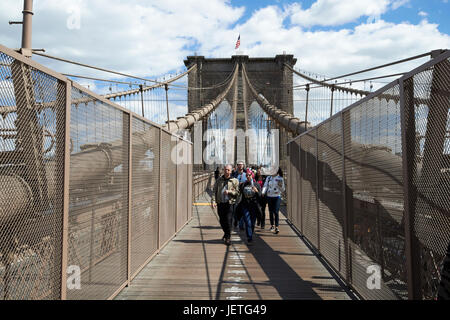people walking over the brooklyn bridge between cables New York City USA