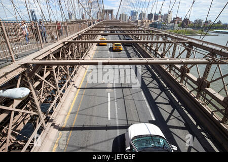 traffic vehicles driving over the worn tarmac on brooklyn bridge New York City USA Stock Photo