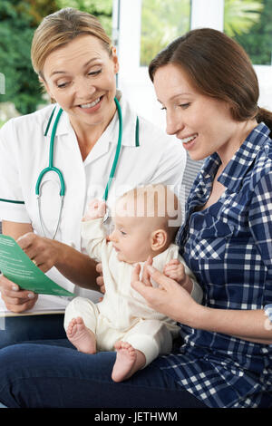 Health Visitor Discussing Leaflet With Mother Holding Baby At Home Stock Photo