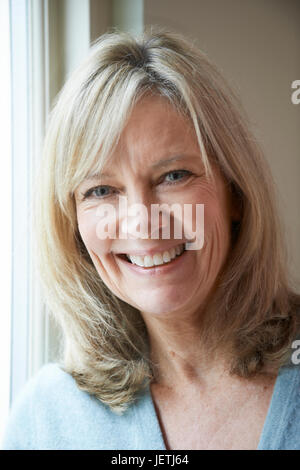 Smiling Mature Woman Standing Next To Window Stock Photo