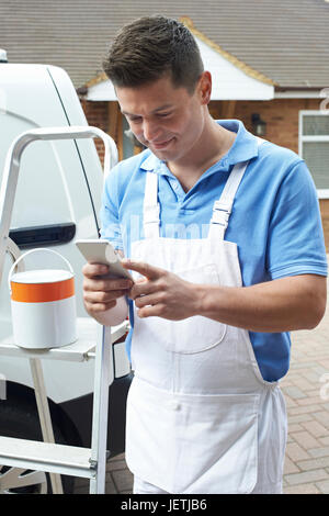 Decorator Using Mobile Phone Standing Outside Domestic Home Stock Photo