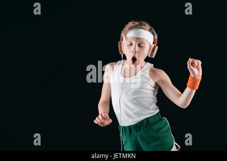 portrait of sportive boy listening music in headphones isolated on black Stock Photo