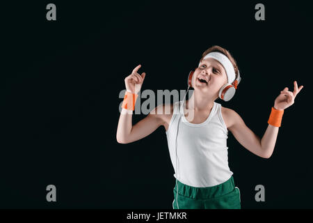 portrait of sportive boy listening music in headphones isolated on black Stock Photo