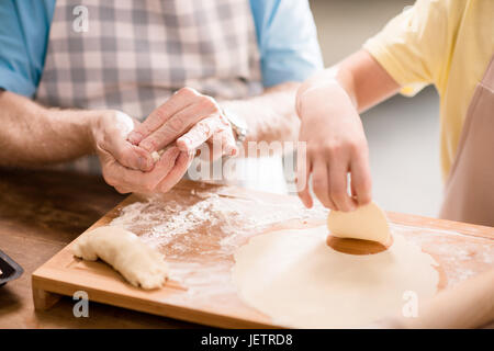 grandchild and grandfather cooking and making dough for cookies with kitchen utensils at kitchen table, cooking in kitchen concept Stock Photo