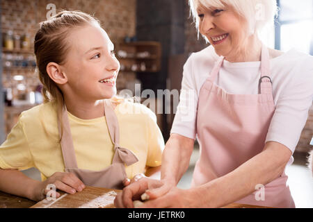 grandmother and child cooking in kitchen and kneading dough for cookies, grandma kitchen concept Stock Photo