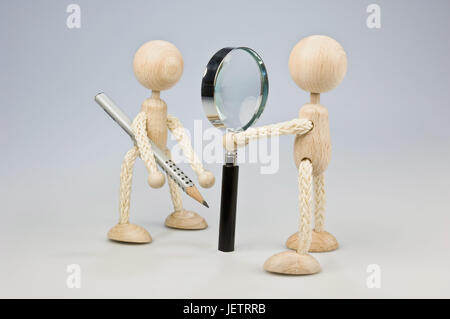 Two wooden figures, one with magnifying glass, one with pencil, Zwei Holzfiguren, eine mit Lupe, eine mit Bleistift Stock Photo
