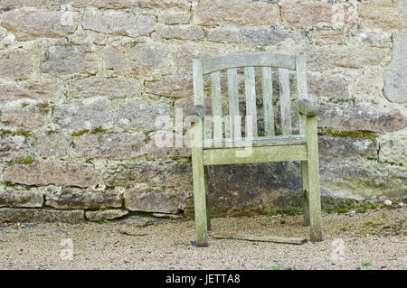 Rotting chair before a natural stone wall, Verrottender Stuhl vor einer Natursteinmauer Stock Photo