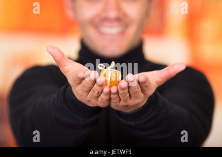 QUITO, ECUADOR- 17 OCTOBER, 2015: Close up of a young man holding in his hands a golden gift present. Stock Photo