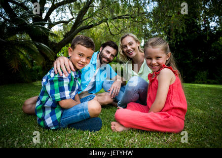 Happy family siting on grass in yard Stock Photo