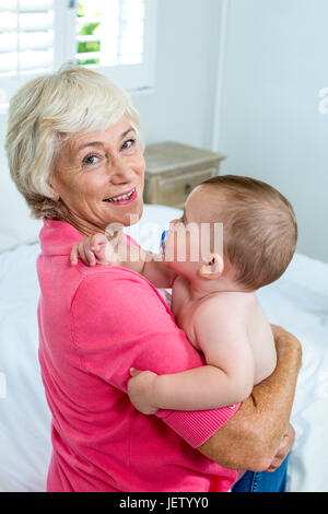 Grandmother carrying baby boy on bed Stock Photo