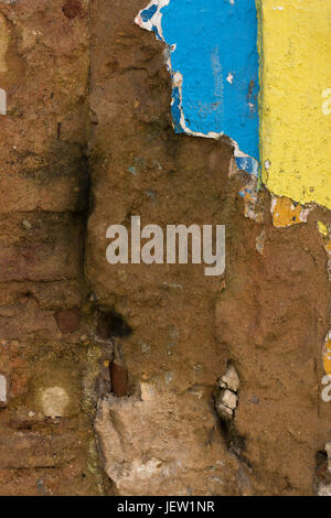 Detail of damaged facade wall with blue and yellow colours. Stock Photo