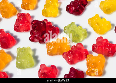 Detail of group of gummy bears lying on the ground except one, which is standing, with isolated background Stock Photo