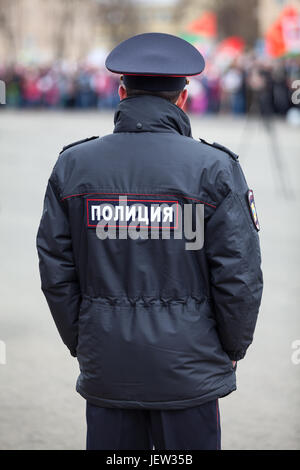 Policeman officer standing back to camera with inscription Police in Russian on the uniform jacket Stock Photo