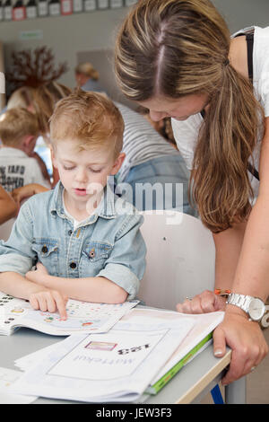 Teacher helping boy at school Stock Photo
