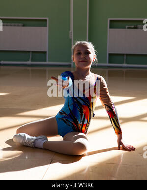 Portrait of an eight years old girl gymnast on the gym floor in the starting position before the performance Stock Photo