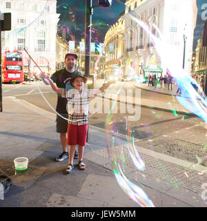 LONDON, ENGLAND - JULY 12, 2016 Street actor inflates big soap bubbles on Piccadilly Street Stock Photo