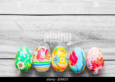 Easter handmade eggs painted in colorful floral patterns placed on wooden table. Stock Photo