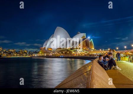 SYDNEY, AUSTRALIA - APRIL 21: Long exposure of people sitting by the Opera bar next to Sydney Opera house in the evening. April 2016. Stock Photo