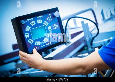 Worker programming print screening machine on the monitor. Industrial printer. Manufacture work. Stock Photo