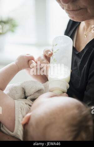 Grandmother bottle feeding baby Stock Photo