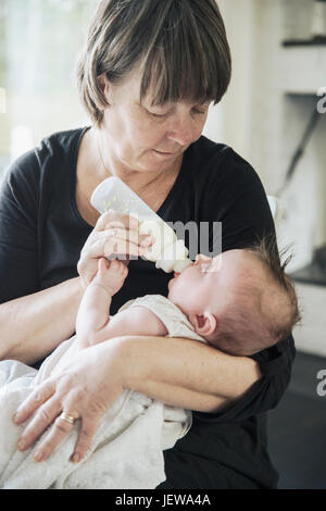 Grandmother bottle feeding baby Stock Photo