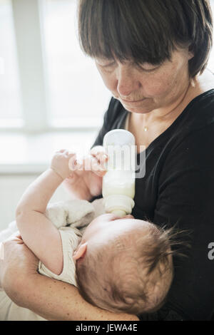 Grandmother bottle feeding baby Stock Photo