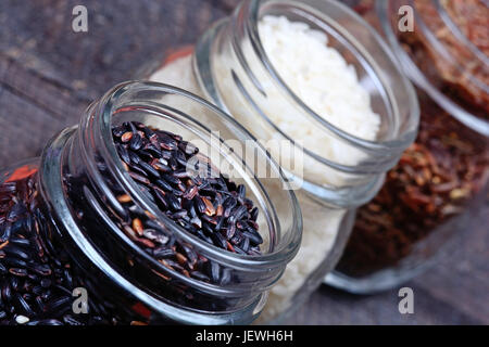 Different types of rice in a jars on wooden table Stock Photo