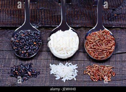 Different types of rice in a spoons on wooden table Stock Photo