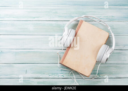 Audio book concept. Headphones and old book over wooden table. Top view with space for your text Stock Photo