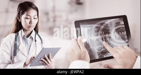 Composite image of asian doctor using tablet Stock Photo