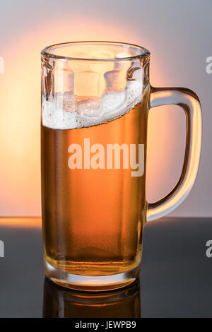 Large glass mug with a light beer covered with droplets on a mirror black surface Stock Photo