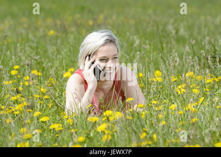 woman with smartphone on flower meadow Stock Photo