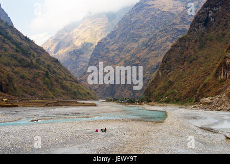 Marsyangdi river and village of Tal, Annapurna circuit, Nepal. Local people breaking rocks for construction can be seen in the foreground. Stock Photo
