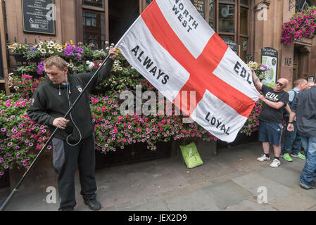 London, UK. 24th June, 2017. Two of the around 40 EDL protesters get their flag ready outside the Wetherspoons pub on Whitehall. Later police escorted them to Charing Cross and down a backstreet to the Embankment where they were to hold a rally. Earlier police had moved several hundred anti-fascist counter-protesters organised by UAF from their route down to a separate area of the Embankment a short distance away where they continued to protest noisily against the EDL until the police escorted them back to Charing Cross station. Both EDL and UAF had conditions for their protests im Stock Photo