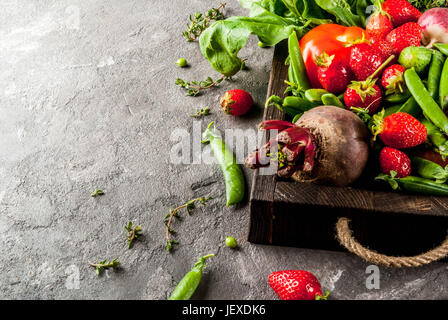 Market. Healthy vegan food. Fresh vegetables, berries, greens and fruits in wooden tray: spinach mint thyme strawberry carrots beets cucumbers radish  Stock Photo