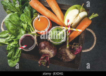 Vegan diet food. Detox drinks. Freshly squeezed juices and smoothies from vegetables: beets, carrots, spinach, cucumber, apple. On dark stone backgrou Stock Photo