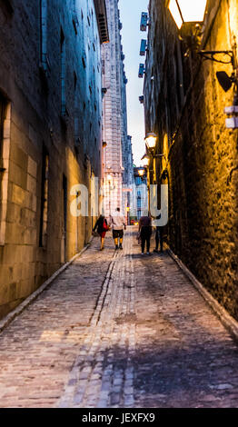 Montreal, Canada - May 27, 2017: Old town area with people walking up street in evening outside empty alleys in Quebec region city Stock Photo