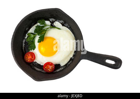 Black cast iron frying pan with fried egg isolated on white background, from above Stock Photo