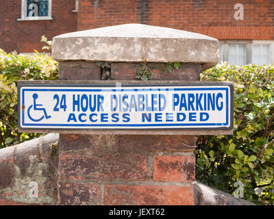 blue and white 24 hour disabled parking access sign on brick post outside Stock Photo