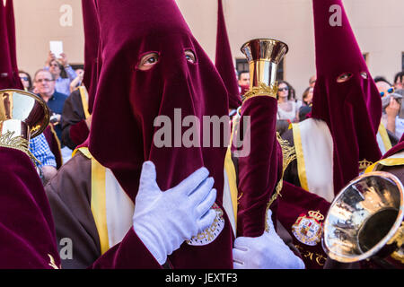 Linares, Jaen province, SPAIN - March 17, 2014: Nazarenes with red tunics and trumpets in the hands of penance during station, taken in Linares, Jaen  Stock Photo