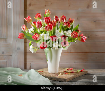 bouquet of red blooming tulips with green leaves, wrapped gift tied ...